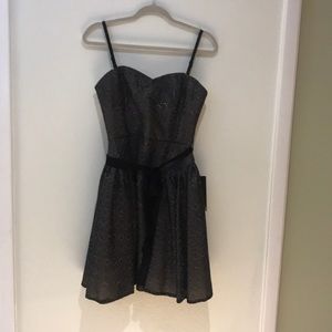 A short black dress with silver design stitching.